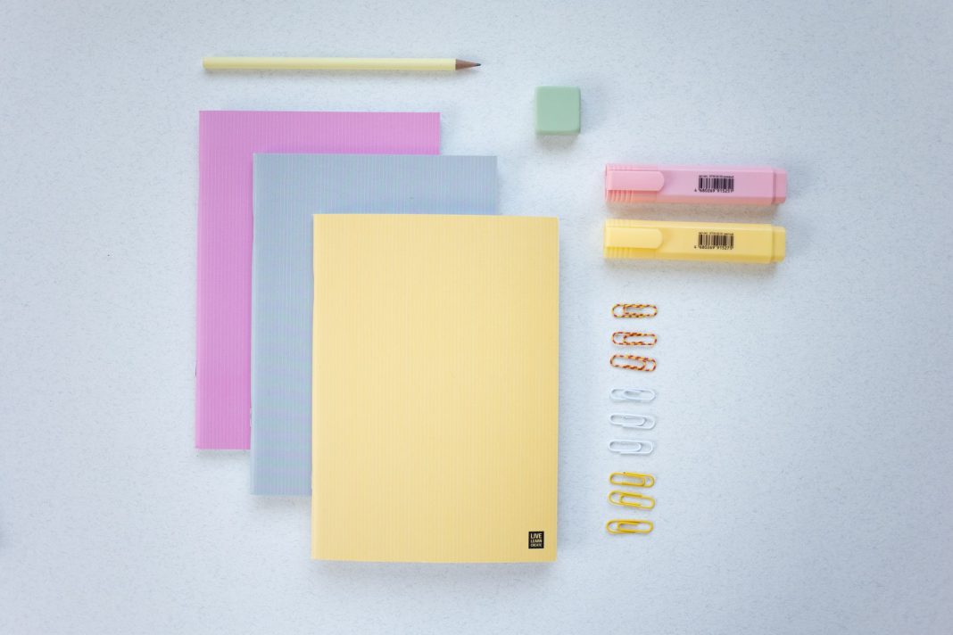 Cuadernos, subrayadores y material escolar sobre una mesa.